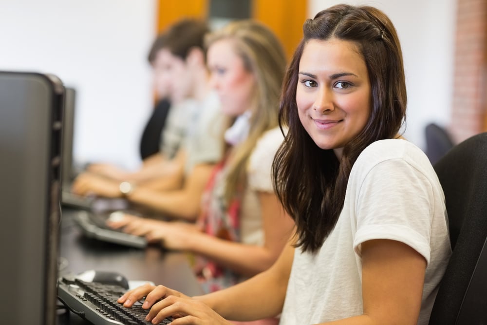 Woman sitting at the computer while smiling in college computer room
